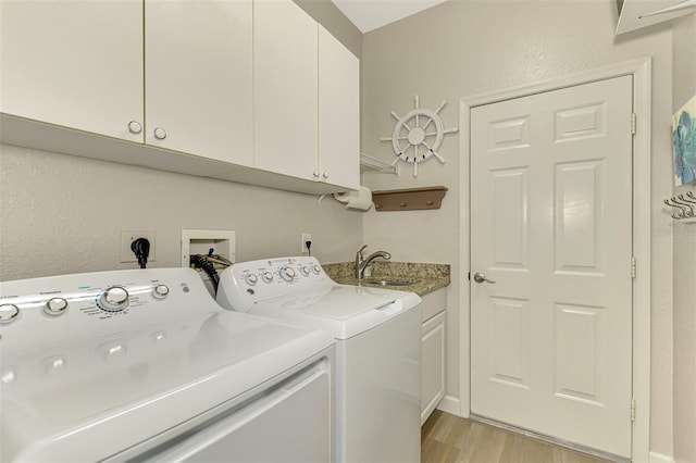 laundry area featuring light hardwood / wood-style floors, cabinets, sink, and washing machine and clothes dryer