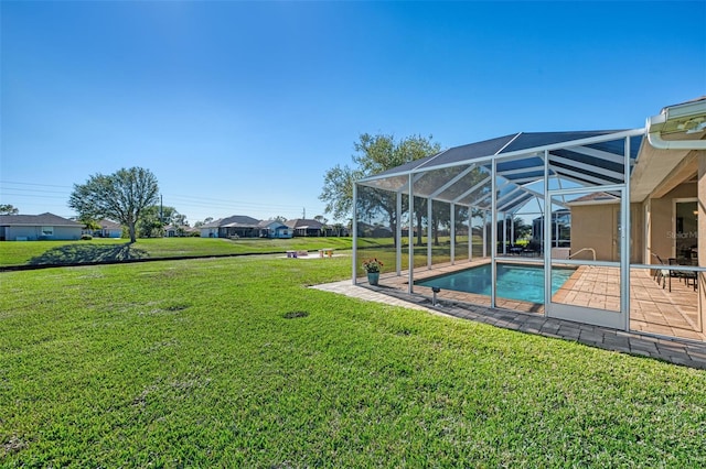 view of pool featuring glass enclosure, a yard, and a patio