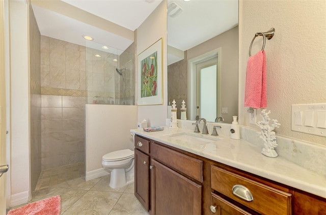 bathroom featuring a tile shower, vanity, toilet, and tile patterned floors