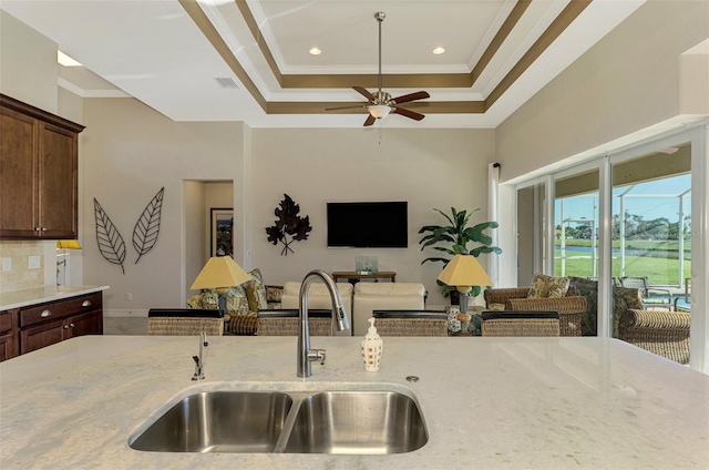 kitchen with a raised ceiling, sink, and ornamental molding