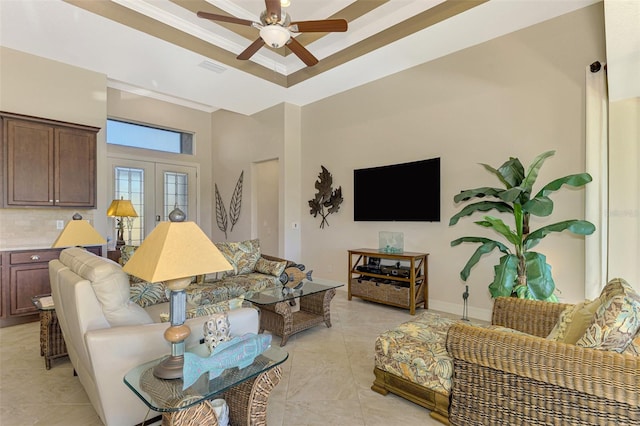 tiled living room with a high ceiling, french doors, a raised ceiling, crown molding, and ceiling fan