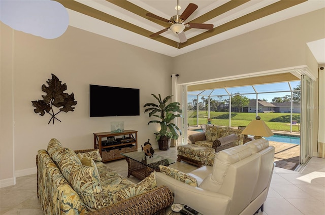 living room featuring a tray ceiling, ceiling fan, and light tile patterned floors