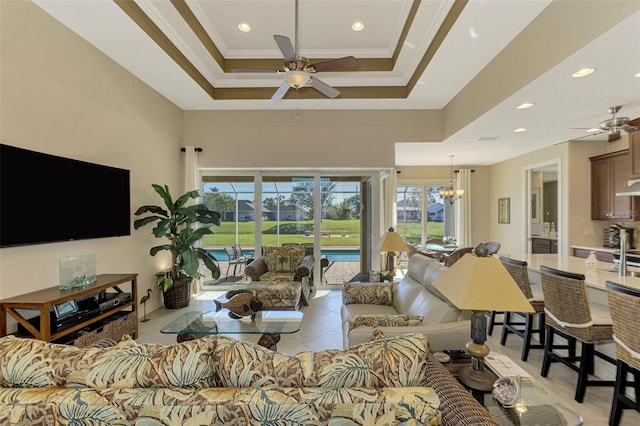 living room featuring ceiling fan with notable chandelier, a raised ceiling, ornamental molding, and light tile patterned floors