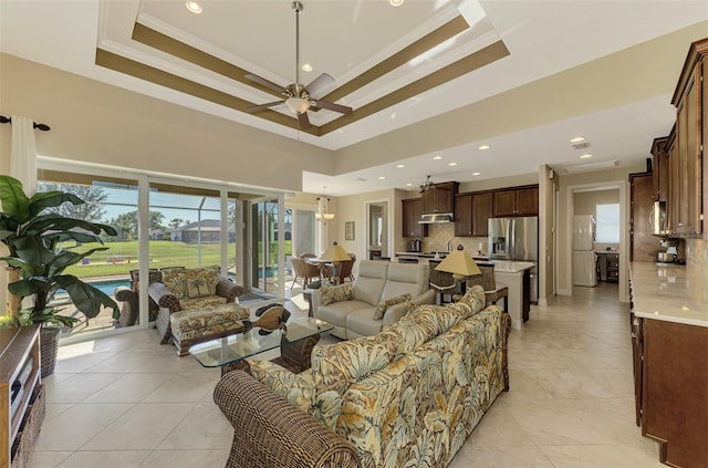 living room featuring ceiling fan, light tile patterned floors, ornamental molding, and a tray ceiling