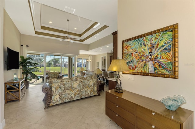 living room with a tray ceiling, ceiling fan, and ornamental molding