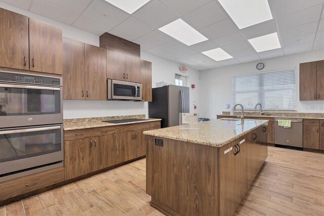 2 Marker Rd, Rotonda West, FL 33947 - kitchen featuring appliances with stainless steel finishes, light wood-style floors, a paneled ceiling, a sink, and light stone countertops