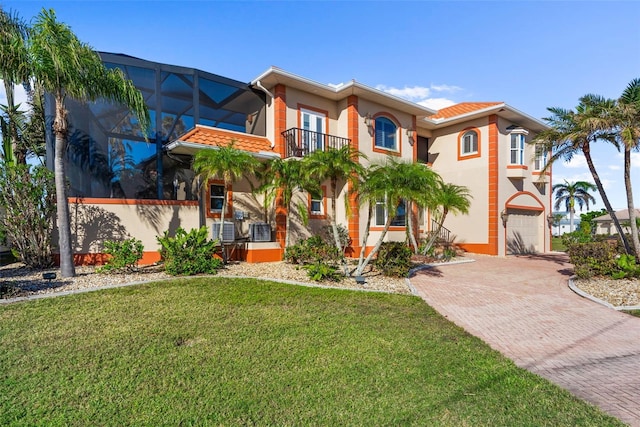 mediterranean / spanish-style home featuring glass enclosure, a balcony, a front lawn, and a garage