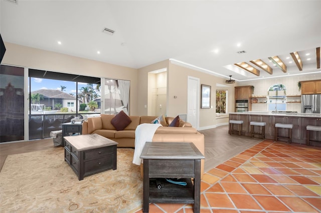 living room with a wealth of natural light, beamed ceiling, and light tile patterned flooring