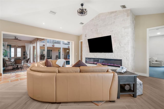 living room featuring a fireplace, light hardwood / wood-style flooring, ceiling fan, and lofted ceiling