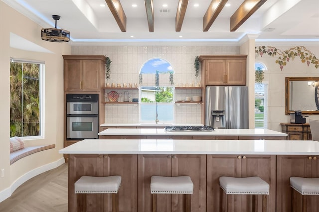 kitchen with stainless steel appliances, light wood-type flooring, a breakfast bar area, decorative backsplash, and ornamental molding