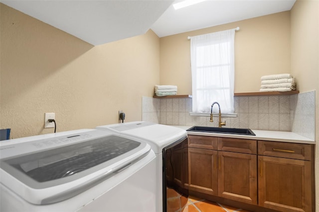 clothes washing area with washing machine and dryer, sink, light tile patterned floors, and cabinets