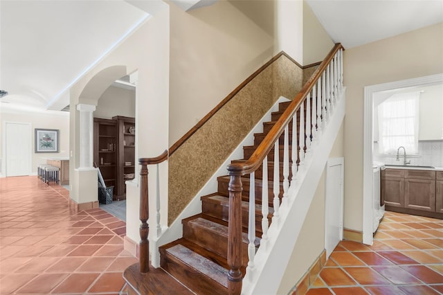 staircase featuring tile patterned flooring, ornate columns, and sink