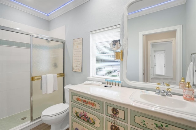 bathroom featuring toilet, vanity, a shower with shower door, and ornamental molding