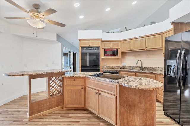 kitchen with light stone countertops, black appliances, vaulted ceiling, and light wood-type flooring