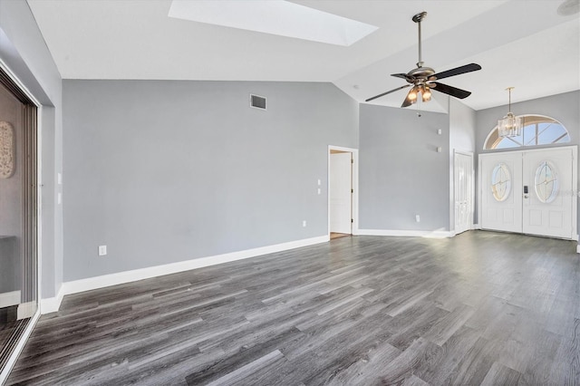 unfurnished living room featuring vaulted ceiling with skylight, dark hardwood / wood-style floors, and ceiling fan