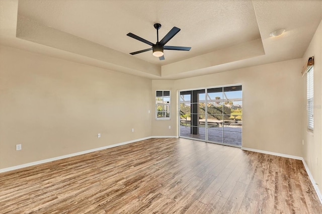 spare room featuring a textured ceiling, hardwood / wood-style flooring, ceiling fan, and a tray ceiling