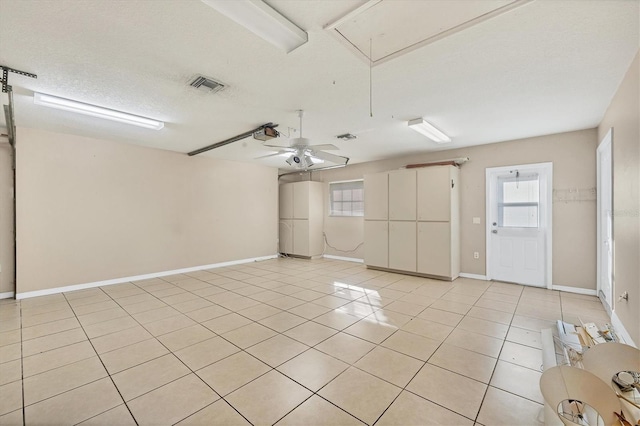 empty room featuring ceiling fan, light tile patterned flooring, and a textured ceiling