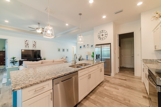 kitchen featuring ceiling fan, sink, stainless steel appliances, an island with sink, and white cabinets