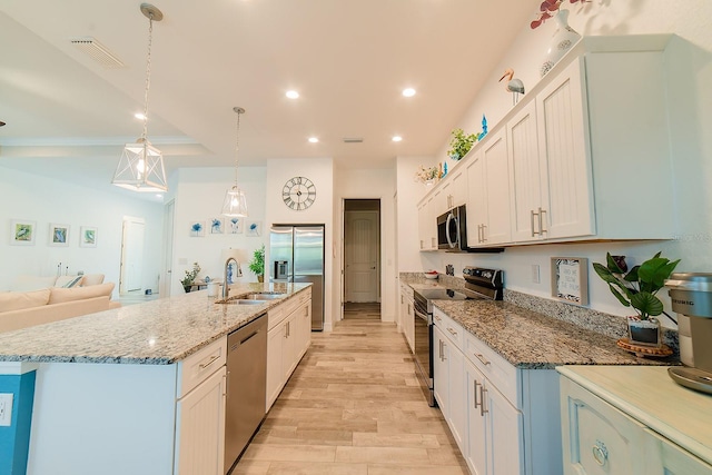 kitchen with sink, an island with sink, appliances with stainless steel finishes, decorative light fixtures, and white cabinetry