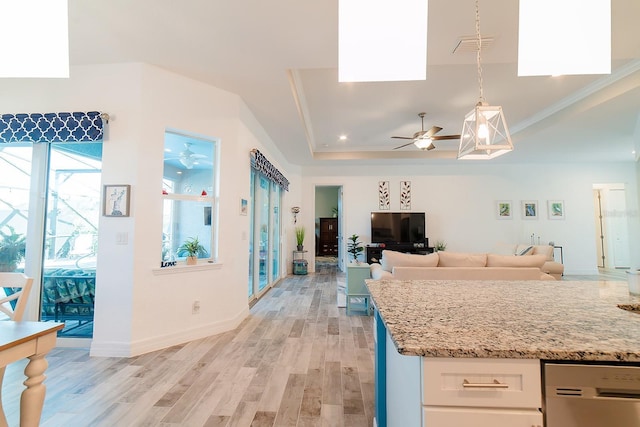 kitchen with white cabinets, light hardwood / wood-style flooring, ceiling fan, a tray ceiling, and decorative light fixtures