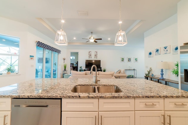 kitchen featuring a raised ceiling, white cabinetry, stainless steel dishwasher, and sink