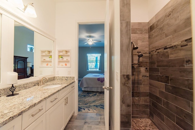 bathroom with ceiling fan, tiled shower, and vanity