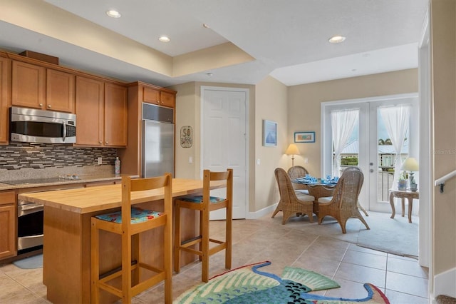 10390 Longshore Rd Unit 82, Placida, FL 33946 - kitchen with stainless steel appliances, wood counters, tasteful backsplash, a kitchen breakfast bar, and french doors