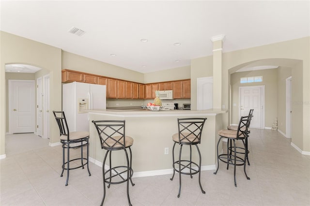 kitchen featuring a breakfast bar, white appliances, and light tile patterned floors