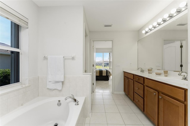 bathroom with tile patterned flooring, vanity, and tiled bath