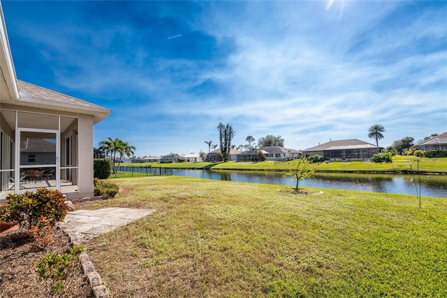 view of yard with a sunroom and a water view