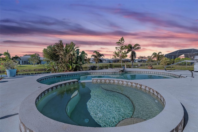 pool at dusk with an in ground hot tub