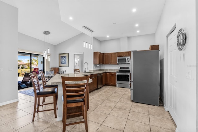 kitchen featuring sink, stainless steel appliances, kitchen peninsula, decorative light fixtures, and light tile patterned flooring