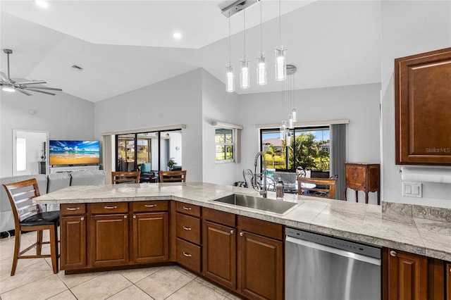 kitchen featuring pendant lighting, dishwasher, sink, light tile patterned flooring, and a kitchen bar