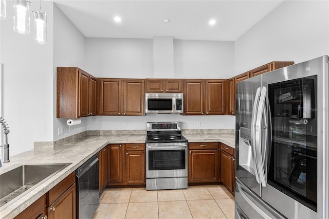 kitchen with sink, hanging light fixtures, light tile patterned floors, a towering ceiling, and appliances with stainless steel finishes