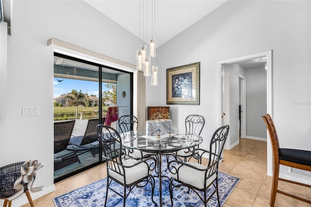 dining room with a notable chandelier, lofted ceiling, and light tile patterned floors