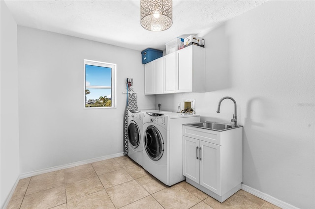 laundry area featuring washer and clothes dryer, cabinets, light tile patterned floors, and sink