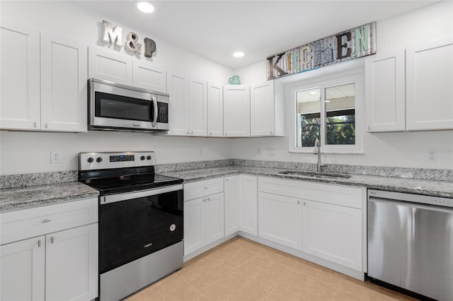 kitchen featuring light stone countertops, appliances with stainless steel finishes, white cabinetry, and sink