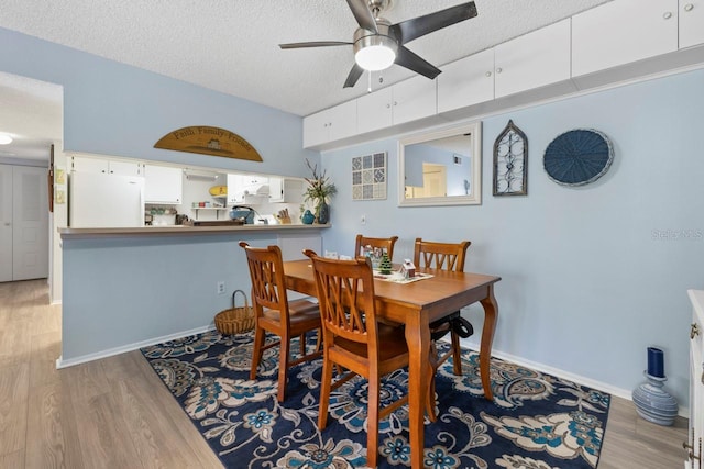 dining space with ceiling fan, a textured ceiling, and light hardwood / wood-style flooring