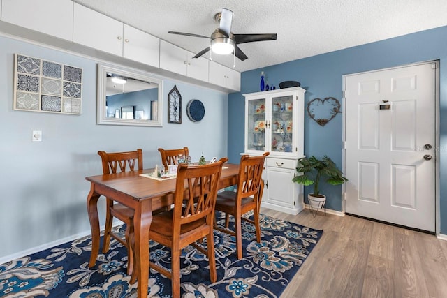 dining space with ceiling fan, a textured ceiling, and light wood-type flooring