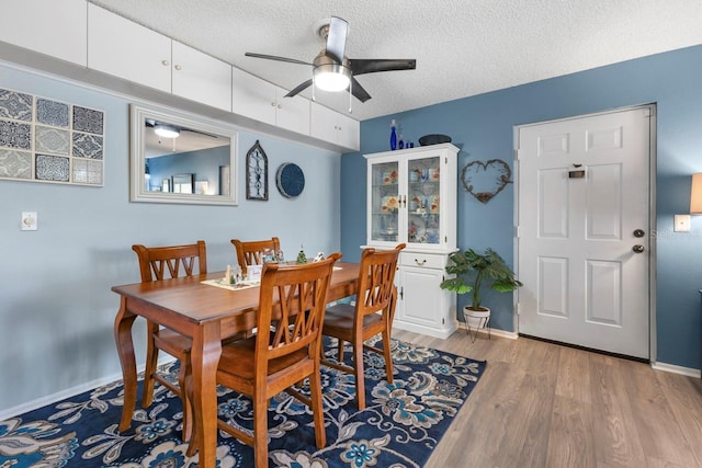 dining space featuring ceiling fan, light wood-type flooring, and a textured ceiling