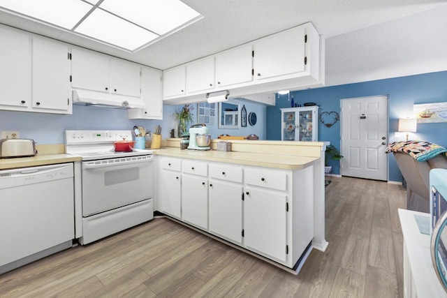 kitchen featuring white appliances, kitchen peninsula, light wood-type flooring, a textured ceiling, and white cabinetry