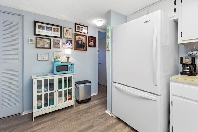 kitchen with white cabinets, dark hardwood / wood-style flooring, white refrigerator, and a textured ceiling