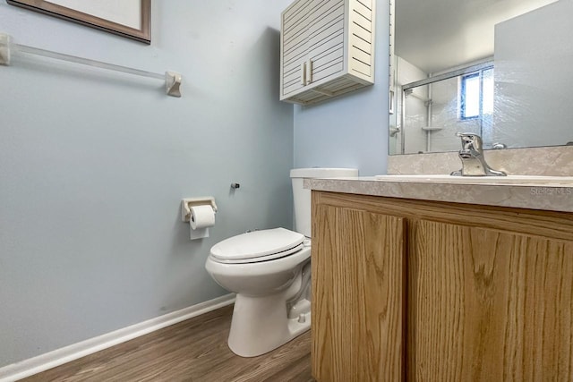 bathroom featuring wood-type flooring, vanity, toilet, and a shower with shower door