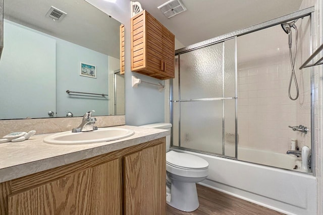 full bathroom with toilet, vanity, wood-type flooring, and combined bath / shower with glass door