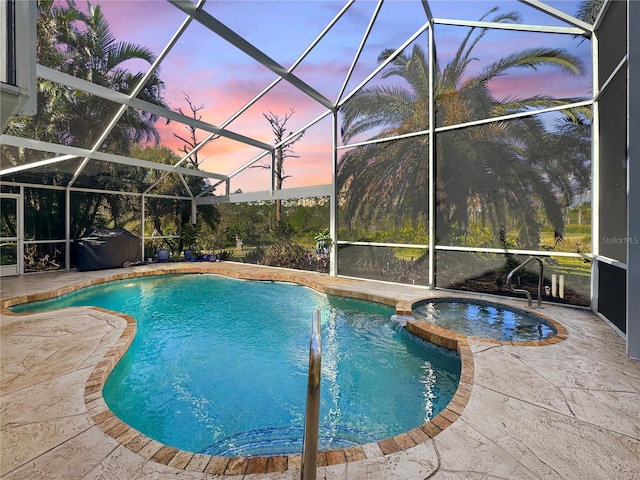 pool at dusk featuring glass enclosure and a patio