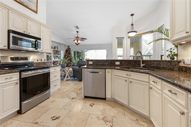 kitchen featuring appliances with stainless steel finishes, pendant lighting, sink, dark stone counters, and ceiling fan