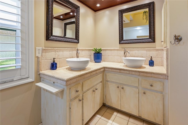 bathroom with tasteful backsplash, vanity, a healthy amount of sunlight, and tile patterned flooring