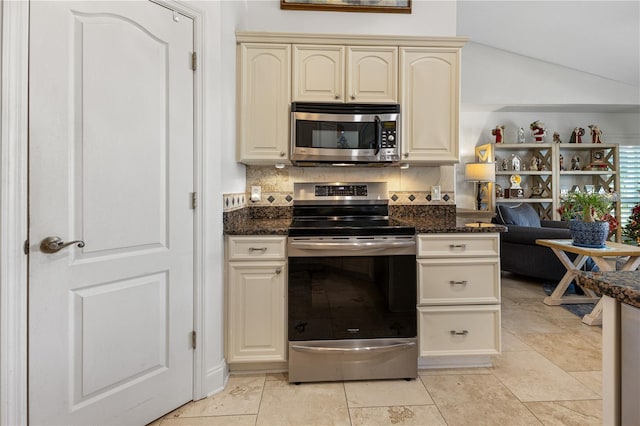 kitchen featuring backsplash, stainless steel appliances, cream cabinets, and dark stone counters