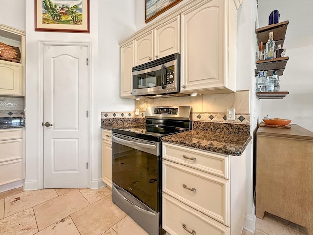 kitchen with tasteful backsplash, stainless steel appliances, cream cabinets, and dark stone counters