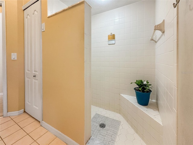 bathroom with a tile shower and tile patterned floors